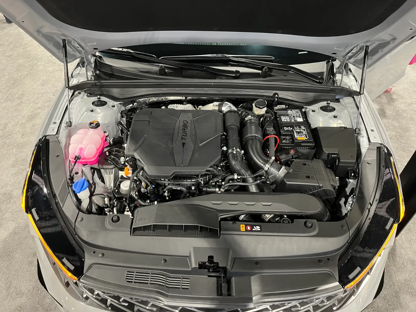 The engine bay of a silver car with the hood held open